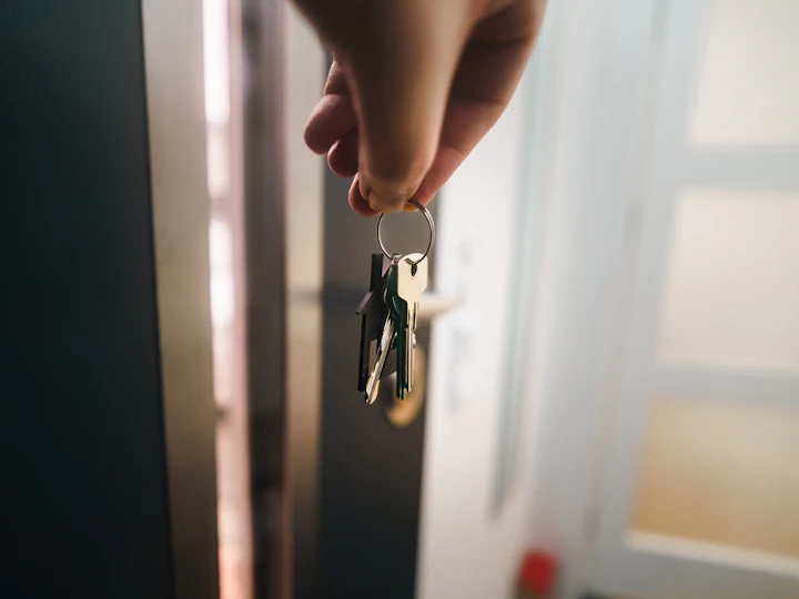Hand hält einen Schlüsselbund vor einer geöffneten Wohnungstür